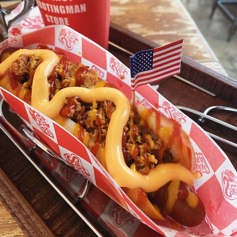A loaded cheddar cheese hot dog with a little American flag